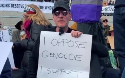 Le leader de Massive Attack, Robert Del Naja, tient une pancarte sur laquelle on peut lire « Je m'oppose au génocide, je soutiens Palestine Action », le 11 avril 2026, en solidarité avec le groupe anti-israélien interdit car répertorié comme organisation terroriste après avoir pénétré dans des usines de défense et une base de la Royal Air Force en faisant des millions de livres de dégâts et en agressant un policier. (Capture d'écran via La Jornada sur YouTube)