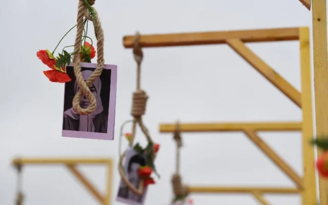 Une photo montre le portrait d'un opposant iranien et des fleurs déposées sur une potence, lors d'une manifestation organisée par l'opposition iranienne en exil pour protester contre le gouvernement iranien, le 8 février 2019 à Paris. (Crédit: Alain JOCARD / AFP)