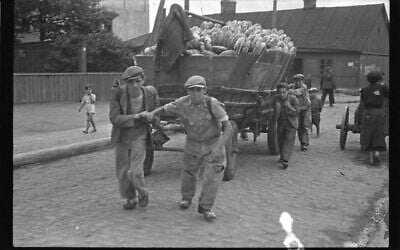 Dans la Pologne occupée par les nazis, des détenus du ghetto de Lodz tirent un chariot de pain destiné à la distribution à l'intérieur du ghetto (Crédit : Henryk Ross)