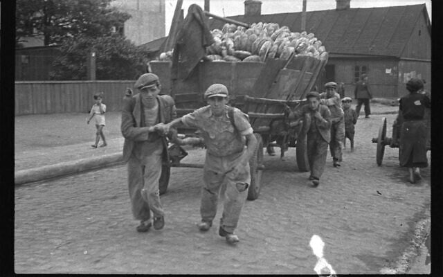 En Pologne occupée par les nazis, des détenus du ghetto de Łódź tirant une charrette de pain destinée à la distribution à l’intérieur du ghetto. (Crédit : Henryk Ross)
