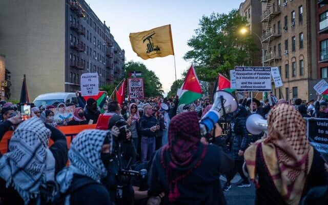 Des manifestants antisionistes brandissant un drapeau du groupe terroriste chiite libanais du Hezbollah, à New York, le 11 mai 2026. (Crédit : Luke Tress/Times of Israel)