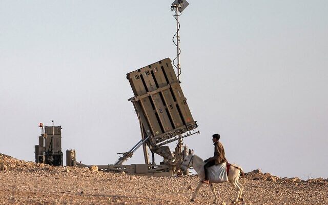 Un garçon montant un âne près d'une batterie du système de défense anti-missile "Dôme de fer", dans un village bédouin non reconnu dans le sud du Neguev, le 14 avril 2024. (Crédit : Ahmad Gharabli/AFP)
