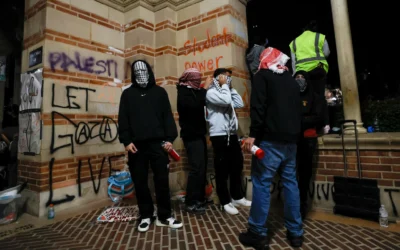 Des jeunes, le visage masqué, installés dans un campement mis en place par des étudiants et des militants pro-palestiniens  manifestent sur le campus de l'Université de Californie à Los Angeles (UCLA), à Los Angeles, en Californie, le 1er mai 2024. (Crédit: Etienne Laurent/AFP)
