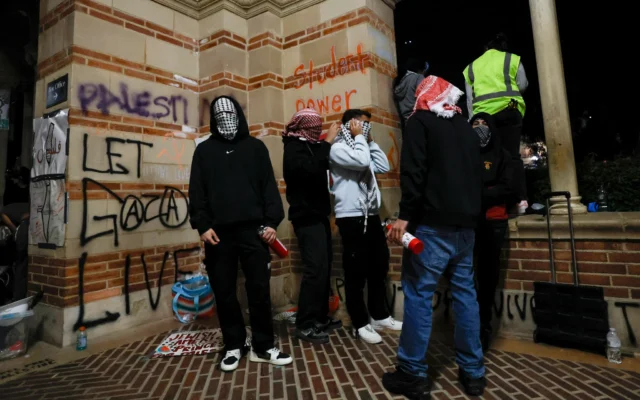 Des jeunes, le visage masqué, installés dans un campement mis en place par des étudiants et des militants pro-palestiniens manifestent sur le campus de l'Université de Californie à Los Angeles (UCLA), à Los Angeles, en Californie, le 1er mai 2024. (Crédit: Etienne Laurent/AFP) Des jeunes, le visage masqué, installés dans un campement mis en place par des étudiants et des militants pro-palestiniens manifestent sur le campus de l'Université de Californie à Los Angeles (UCLA), à Los Angeles, en Californie, le 1er mai 2024. (Crédit: Etienne Laurent/AFP)