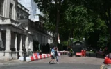 Des passants devant l'entrée fermée de la rue où se trouve l'ambassade d'Israël à Londres, le 15 juin 2025. (Crédit : Justin Tallis/AFP)