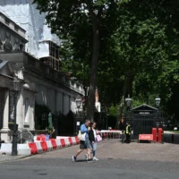 Des passants devant l'entrée fermée de la rue où se trouve l'ambassade d'Israël à Londres, le 15 juin 2025. (Crédit : Justin Tallis/AFP)