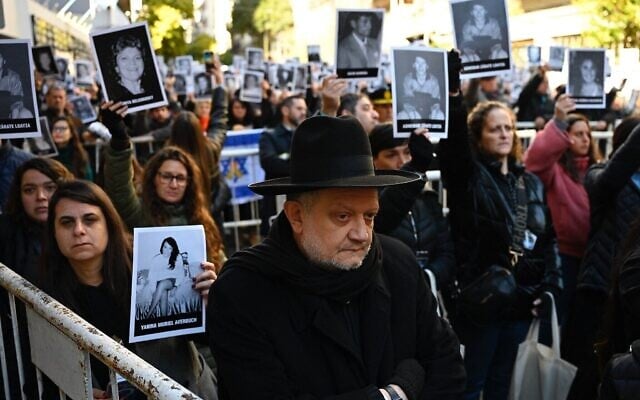 Des personnes tenant des photos des victimes lors d’une cérémonie commémorant le 31ᵉ anniversaire de l’attentat à la bombe contre l’AMIA, qui a fait 85 morts et plus de 300 blessés, à Buenos Aires, en Argentine, le 18 juillet 2025. (Crédit : Luis Robayo/AFP)