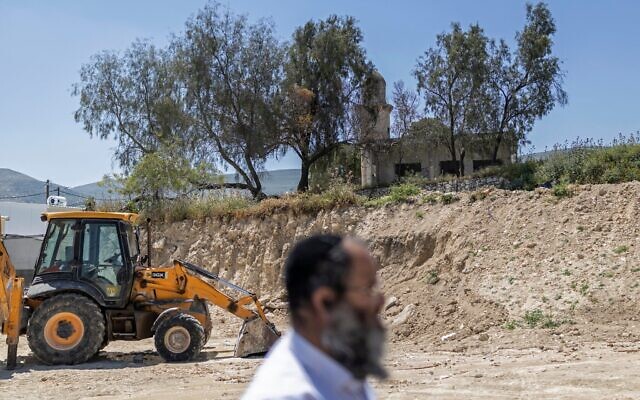 Le résident d'implantation Meïr Goldmintz passant devant un bulldozer à l'arrêt, dans l'implantation de Sa-Nur, au sud de Jénine en Cisjordanie, le 7 mai 2026. (Crédit : Ilia Yefimovich/AFP) Le résident d'implantation Meïr Goldmintz passant devant un bulldozer à l'arrêt, dans l'implantation de Sa-Nur, au sud de Jénine en Cisjordanie, le 7 mai 2026. (Crédit : Ilia Yefimovich/AFP)