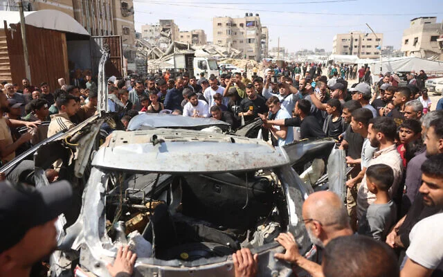 Des Palestiniens examinent les restes d'un véhicule détruit par une frappe israélienne à Khan Younès, dans le sud de la bande de Gaza, le 10 mai 2026 (Bashar Taleb / AFP)
