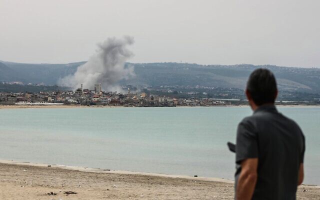 Un homme observant de la fumée s'élevant du site d'une frappe aérienne israélienne dans la région de Ras Al-Ain, depuis la plage près de Tyr, le 12 mai 2026. (Crédit : Kawnat Haju/AFP)
