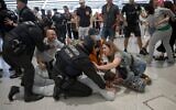 Des agents de la police basque arrêtant des membres de la « Global Sumud Flotilla » à leur arrivée à l'aéroport de Bilbao, le 23 mai 2026. (Crédit : Idurre Etxaburu/AFP)