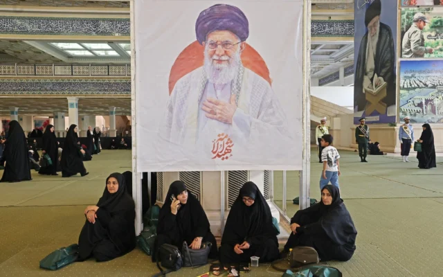 Des Iraniennes sont assises devant une image du guide suprême assassiné Ali Khamenei alors qu’elles se rassemblent à la mosquée de l’imam Khomeini à Téhéran, en Iran, pour une commémoration des morts de la guerre, le 24 mai 2026. (Crédit: ATTA KENARE / AFP)