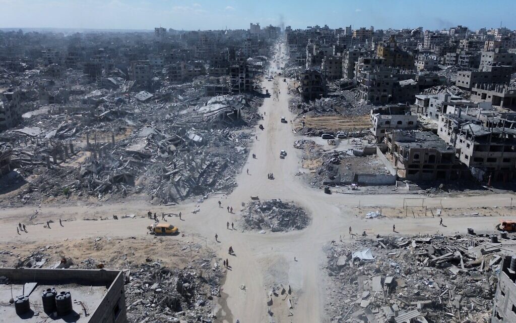 Sur cette photo prise par un drone, on voit des Palestiniens traverser un carrefour entouré de bâtiments détruits par deux années de bombardements israéliens à Gaza City, le mercredi 15 octobre 2025. (Crédit : AP) Sur cette photo prise par un drone, on voit des Palestiniens traverser un carrefour entouré de bâtiments détruits par deux années de bombardements israéliens à Gaza City, le mercredi 15 octobre 2025. (Crédit : AP)