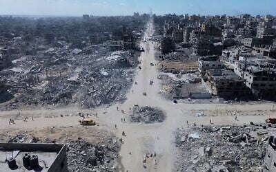 Sur cette photo prise par un drone, on voit des Palestiniens traverser un carrefour entouré de bâtiments détruits par deux années de bombardements israéliens à Gaza City, le mercredi 15 octobre 2025. (Crédit : AP)