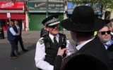 Un policier britannique s'entretient avec un passant après que deux hommes juifs ont été poignardés par un terroriste dans le quartier de Golders Green, qui abrite une importante communauté juive, à Londres, le 29 avril 2026. (Crédit: AP Photo/Kin Cheung)