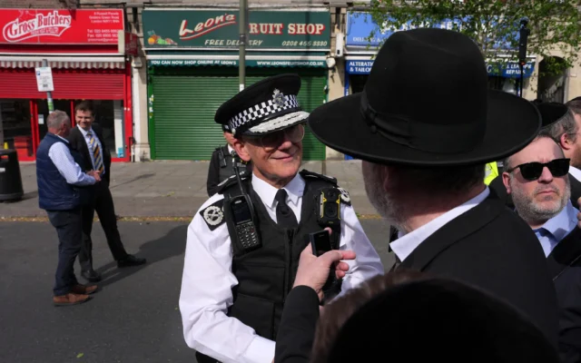 Un policier britannique s'entretient avec un passant après que deux hommes juifs ont été poignardés par un terroriste dans le quartier de Golders Green, qui abrite une importante communauté juive, à Londres, le 29 avril 2026. (Crédit: AP Photo/Kin Cheung)