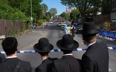 Illustration : Des habitants observant les enquêteurs qui ratissent les lieux après que deux personnes ont été poignardées dans le quartier de Golders Green, qui compte une importante communauté juive, à Londres, le 29 avril 2026. (Crédit : Kin Cheung/AP)