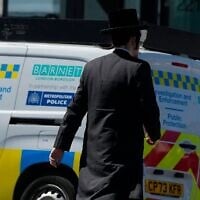 Un homme passant devant un véhicule des services d'enquête et d'intervention, près du lieu où deux Juifs ont été poignardés dans le quartier de Golders Green, à Londres, le 30 avril 2026. (Crédit : Alastair Grant/AP)