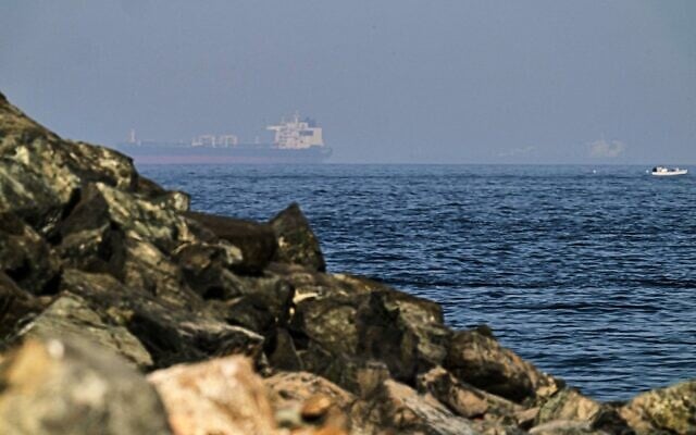 Des cargos en mer dans le golfe d’Oman, près du détroit d’Ormuz, vus depuis une côte rocheuse près de Khor Fakkan, aux Émirats arabes unis, le 1ᵉʳ mai 2026. (Crédit : Fatima Shbair/AP)