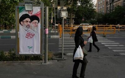 Des femmes passant devant une banderole sur laquelle figurent les portraits du guide suprême iranien, l'ayatollah Mojtaba Khamenei (à gauche), et de son père, l'ayatollah Ali Khamenei, guide suprême éliminé, à Téhéran, en Iran, le 12 mai 2026. (Crédit : Vahid Salemi/AP) Des femmes passant devant une banderole sur laquelle figurent les portraits du guide suprême iranien, l'ayatollah Mojtaba Khamenei (à gauche), et de son père, l'ayatollah Ali Khamenei, guide suprême éliminé, à Téhéran, en Iran, le 12 mai 2026. (Crédit : Vahid Salemi/AP)
