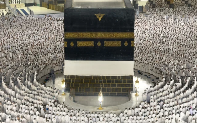 Sur cette photo prise à travers une barrière en verre, des pèlerins musulmans en prière autour de la Kaaba, le lieu le plus sacré de l'islam, à la Grande Mosquée de La Mecque, en Arabie saoudite, lors du pèlerinage annuel du hadj, le 22 mai 2026. (Crédit: AP Photo/Altaf Qadri)