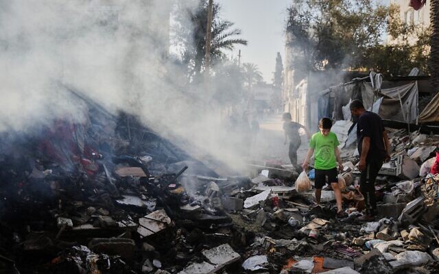 Des Palestiniens marchent parmi les décombres d'une maison détruite lors d'une frappe aérienne israélienne à Deir al-Balah, au centre de la bande de Gaza, le dimanche 24 mai 2026. (Crédit : AP Photo/Abdel Kareem Hana)
