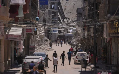 Des Palestiniens marchent dans une rue bordée de bâtiments détruits par les frappes militaires israéliennes pendant la guerre entre Israël et le Hamas à Khan Younès, dans le sud de la bande de Gaza, le 29 mai 2026. (Crédit: AP Photo/Abdel Kareem Hana)