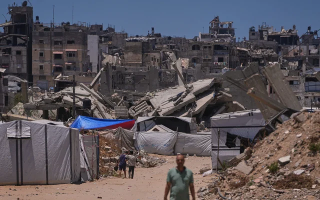 Des Palestiniens marchent dans une rue bordée de bâtiments détruits par les frappes militaires israéliennes pendant la guerre entre Israël et le Hamas à Khan Younis, dans le sud de la bande de Gaza, le 29 mai 2026. (Crédit: AP Photo/Abdel Kareem Hana)