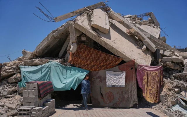 Une membre de la famille Abu Rish se tient devant l'entrée de sa maison effondrée, détruite par des frappes militaires israéliennes pendant la guerre entre Israël et le Hamas, à Khan Younès, dans le sud de la bande de Gaza, le 29 mai 2026. (Crédit: AP Photo/Abdel Kareem Hana)