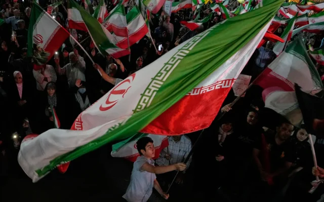 Des manifestants iraniens pro-gouvernementaux brandissent les drapeaux de leur pays lors d'un rassemblement sur une place de Téhéran, en Iran, le 29 mai 2026. (Crédit: AP/Vahid Salemi)