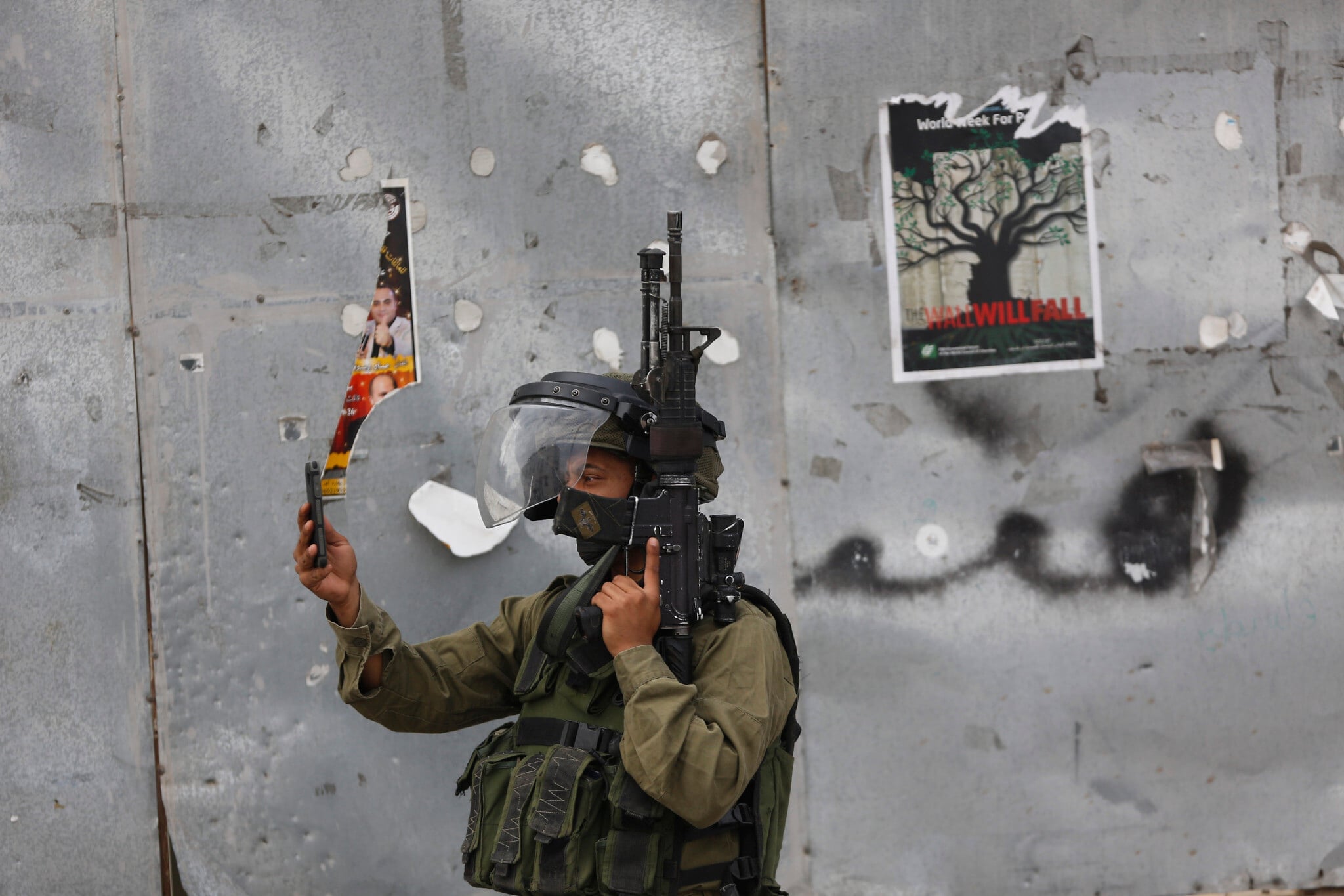 Ilustration : Un soldat israélien prenant une photo avec son téléphone portable lors d'affrontements avec des manifestants palestiniens, dans la ville de Bethléem, en Cisjordanie, le 13 octobre 2015. (Crédit : Nasser Shiyoukhi/AP) Ilustration : Un soldat israélien prenant une photo avec son téléphone portable lors d'affrontements avec des manifestants palestiniens, dans la ville de Bethléem, en Cisjordanie, le 13 octobre 2015. (Crédit : Nasser Shiyoukhi/AP)