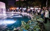 Des personnes observent une minute de silence devant les photos des victimes d'attentats terroristes et des soldats israéliens tombés au combat sur la place Dizengoff à Tel-Aviv, à l'ouverture de la Journée du Souvenir en Israël, le 20 avril 2026. (Crédit : Avshalom Sassoni/Flash90)