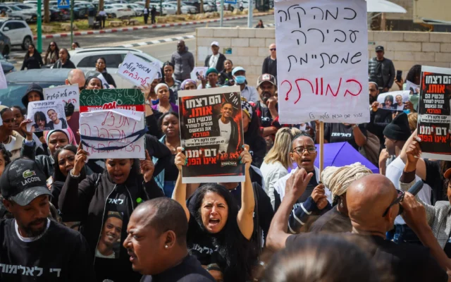 Des manifestants brandissent des pancartes et réclament justice à la suite du meurtre de Yemanu Zelka, un employé de Pizza Hut poignardé à mort la veille de Yom HaAtsmaout, devant un tribunal de Petah Tikva, le 5 mai 2026. (Crédit : Roy Alima/Flash90)