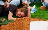 Roee, la veuve du major (Rés.) Itamar Sapir tombé au combat dans le sud du Liban, allongée près de sa tombe lors de ses funérailles, au cimetière militaire de Raanana, le 20 mai 2026. (Crédit : Tal Gal/Flash90)