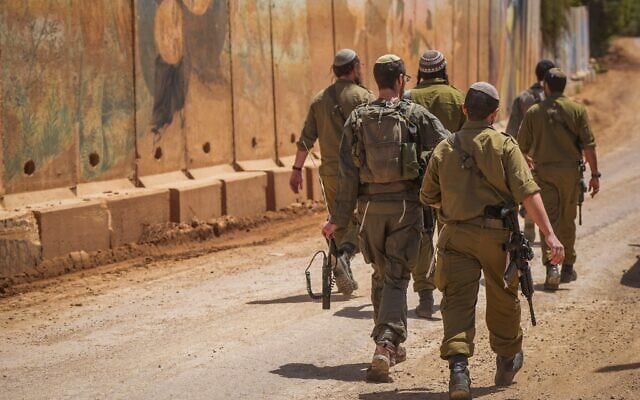 Illustration : Des soldats israéliens marchant près du mur de béton, au moshav Shtula, le long de la frontière israélo-libanaise dans le nord d'Israël, le 27 avril 2026. (Crédit : Ayal Margolin/Flash90)