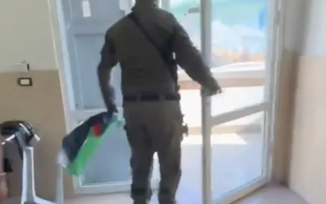 Un policier confisquant un drapeau palestinien au centre our les jeunes du parti Hadash à Umm al-Fahm, le 1er mai 2026. (Capture d'écran/X)