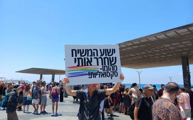 Un homme brandit une pancarte anti-LGBTQ proclamant : "Jésus m’a sauvé de l’homosexualité" avant qu’elle ne soit confisquée par la police, lors de la Tel Aviv Pride, le 12 juin 2026. (Crédit: Noam Lehmann/The Times of Israel)
