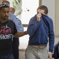 L’Américano-israélien Michael Kadar (à droite), accusé d’avoir proféré des dizaines de menaces antisémites à la bombe aux États-Unis et ailleurs, escorté par des gardes à sa sortie du tribunal de Rishon LeZion, le 23 mars 2017. (Crédit : Jack Guez/AFP)
