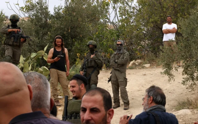Photo d'illustration : des soldats israéliens et des partisans du mouvement pro-implantations se rassemblent dans le village d’Edna, au nord de la ville d’Hébron en Cisjordanie, pendant la saison de la récolte des olives, le 12 octobre 2025. (Crédit: HAZEM BADER / AFP)