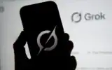 Sur cette illustration photographique, le logo de Grok apparaissant sur un téléphone portable à côté du site web affiché sur un écran d’ordinateur, à Bogota, le 12 février 2026. (Crédit : Pablo Vera/AFP)