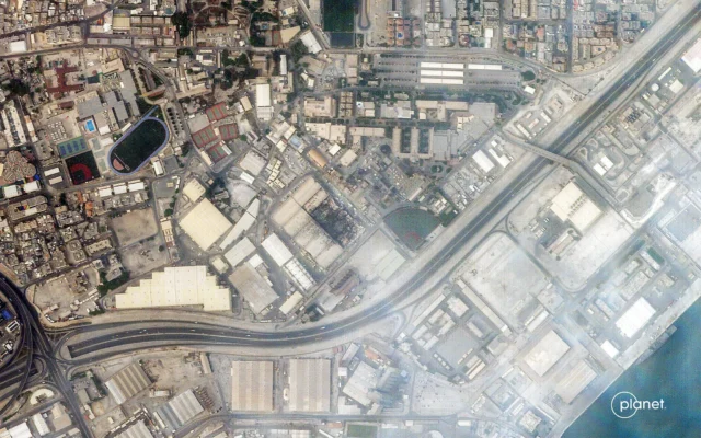 Cette image satellite fournie par 2026 Planet Labs PBC le 1ᵉʳ mars 2026 montre de la fumée s'élevant des dégâts causés à la base navale de la 5ᵉ flotte américaine à Manama, la capitale de Bahreïn, après qu’elle a été frappée par des frappes iraniennes. (Crédit : Planet Labs PBC/AFP)