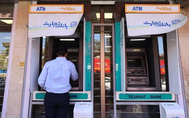 Un homme retirant de l'argent à un distributeur de la Banque Tejarat, à Téhéran, le 25 mai 2026. (Crédit : Atta Kenare/AFP)