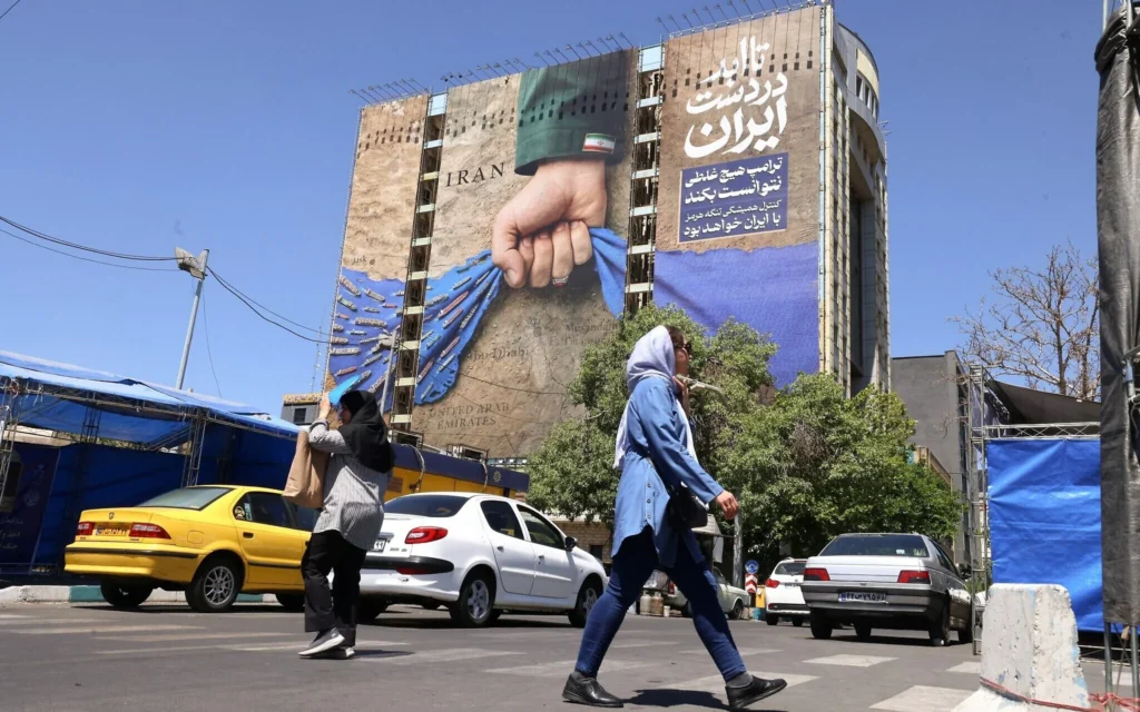 Un panneau d'affichage sur la façade d'un immeuble représentant le détroit d'Ormuz, avec une légende en persan indiquant "Pour toujours entre les mains de l'Iran", sur la place Vanak à Téhéran, le 25 mai 2026. (Crédit: ATTA KENARE / AFP)