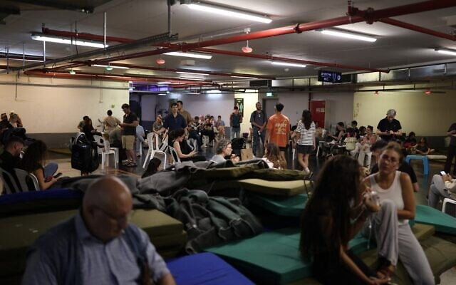 Des personnes s'abritant dans un parking souterrain lors d'une alerte  aux missiles, à Tel Aviv, le 8 juin 2026 (Crédit : Ilia Yefimovich/AFP)