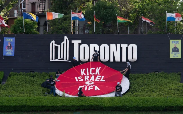Des militants placent une banderole recouvrant le logo de la Coupe du monde de la FIFA 2026 avec les mots "Sortez Israël de la FIFA" à Toronto, au Canada, le 12 juin 2026. (Crédit: Jorge UZON / AFP)