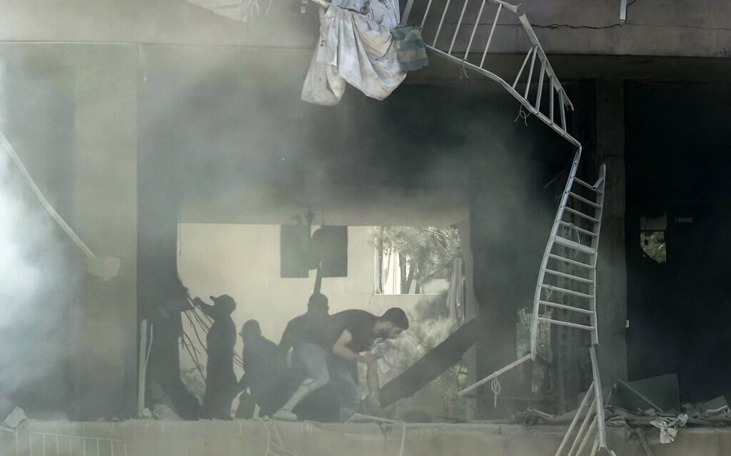 Des personnes recherchant des survivants sur le site d'une frappe aérienne israélienne qui visait un centre de commandement du Hezbollah - bastion historique du groupe terroriste chiite libanais connu sous le nom de la Dahiyeh -, dans la banlieue sud de Beyrouth, au Liban, le 14 juin 2026. (Crédit : Ibrahim Amro/AFP)