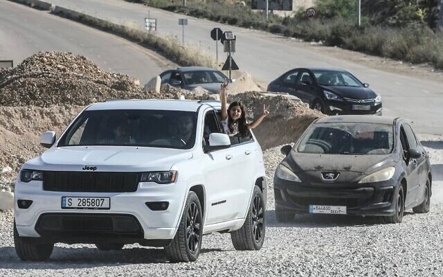 Une fillette faisant le signe de la victoire depuis un véhicule alors que des habitants déplacés traversent le pont de Bourj Rahal pour rejoindre leur village, dans le sud du Liban, le 15 juin 2026. (Crédit : Kawnat Haju/AFP)