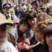 Des personnes rassemblées pour suivre le déroulement des audiences, alors qu'un bras de fer juridique oppose le gouvernement britannique au groupe anti-Israël Palestine Action classé organisation terroriste, devant le Royal Courts of Justice, dans le centre-ville de Londres, le 15 juin 2026. (Crédit : Carlos Jasso/AFP)