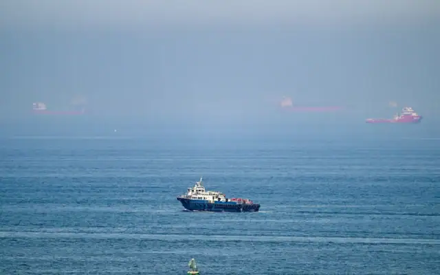 Illustration : Des cargos au large du terminal à conteneurs de Khor Fakkan, le seul port naturel en eau profonde de la région et l’un des principaux ports à conteneurs de l’émirat de Sharjah, le long du golfe d’Oman, le 19 juin 2026. (Crédit : AFP)