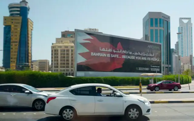 Photo d'illustration : Des voitures passent devant un panneau d’affichage sur lequel oest écrit "Le Bahreïn est en sécurité… Parce que vous en êtes le peuple", à Manama, le 25 juin 2026. (Crédit: Eric Lee / POOL / AFP)